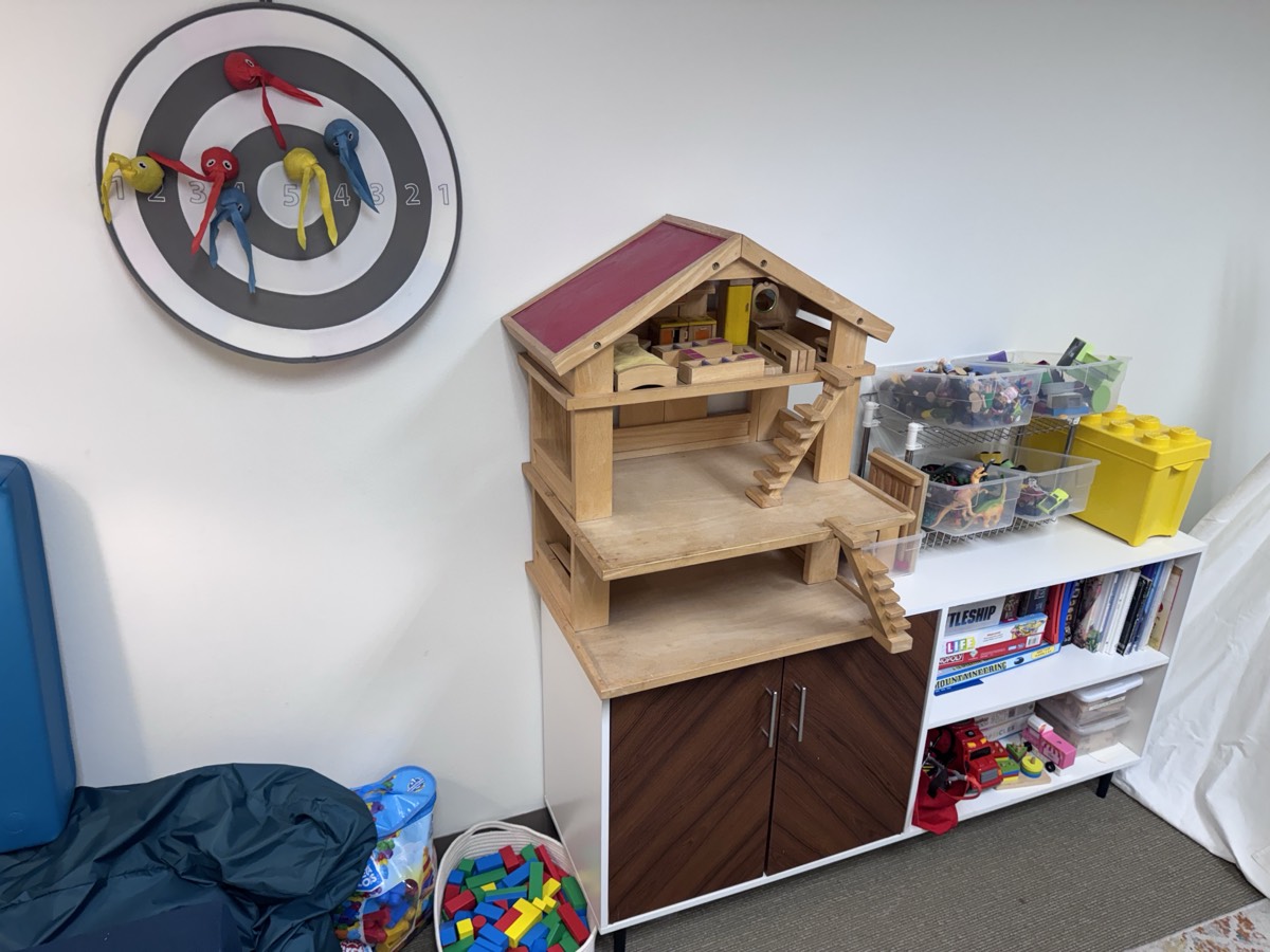 A doll house, dart board, and blocks in the playroom